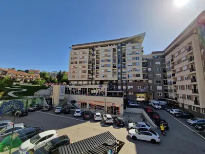 a parking lot with cars parked in front of a building at Plavi Paun Apartman in Belgrade