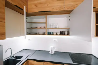 a kitchen with white walls and wooden cabinets at Apartman Biser 5 in Ruma