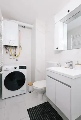 a white bathroom with a toilet and a microwave at Apartman Biser 5 in Ruma