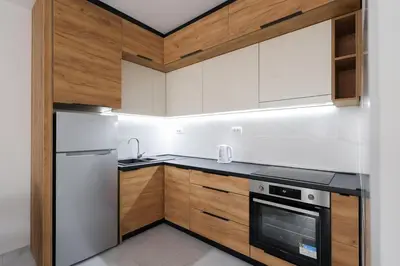 a kitchen with white appliances and wooden cabinets at Apartman Biser 5 in Ruma