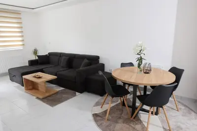 a living room with a black couch and a table at Apartman Biser 5 in Ruma