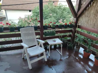 a white chair sitting on a patio with potted plants at Icy Apartment in Belgrade