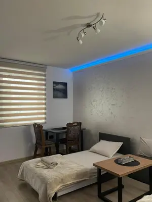a room with two beds and a table and a blue light at Apartman Silver Bg in Kneževac