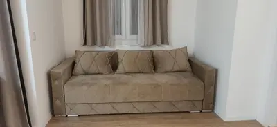 a brown couch sitting in a corner of a room at Apartman Andjela in Surčin