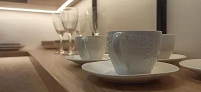 three cups and saucers on a wooden table with wine glasses at Apartman Andjela in Surčin