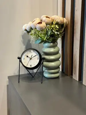 a clock and a vase with flowers on a table at Fairy tale apartment 8 in Voždovac
