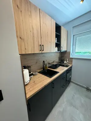 a kitchen with wooden cabinets and a sink and a window at Fairy tale apartment 8 in Voždovac