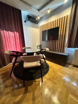 a room with a table and chairs and a television at Fairy tale apartment 8 in Voždovac