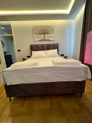 a large bed in a bedroom with a tree painting on the wall at Fairy tale apartment 8 in Voždovac