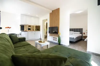 a living room with a green couch and a bedroom at Uba Fruška gora in Velika Remeta