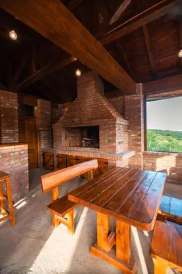 a room with a wooden table and a brick fireplace at Uba Fruška gora in Velika Remeta