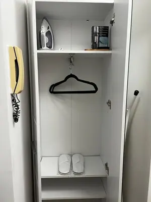 a small white closet with a phone and shelves at View in Zvezdara