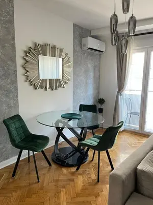 a dining room with a glass table and green chairs at Sanja, Old Town in Belgrade