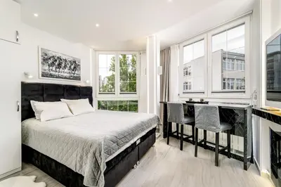 a bedroom with a bed and a desk and windows at New Urban Studio in Belgrade