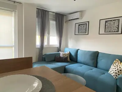a living room with a blue couch and a table at Apartman Peric in Ruma