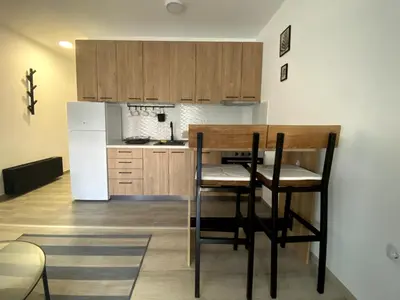 a kitchen with a table and a white refrigerator at Apartman Peric in Ruma