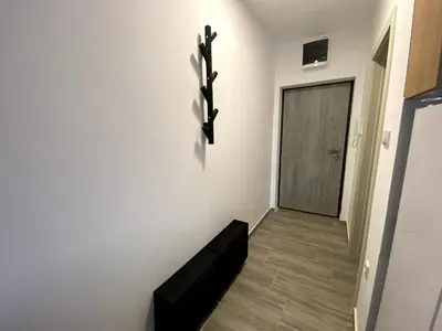 a hallway with a black bench and a door at Apartman Peric in Ruma