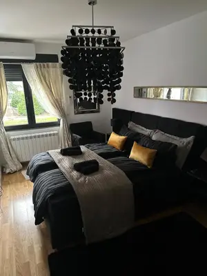 a bedroom with a large bed and a chandelier at Lux Tea Pancevo in Pančevo