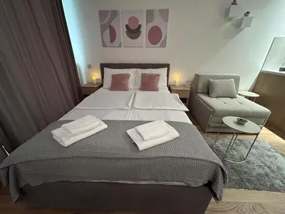 a bedroom with a large bed and a chair at V Park Lux Apartman in Belgrade