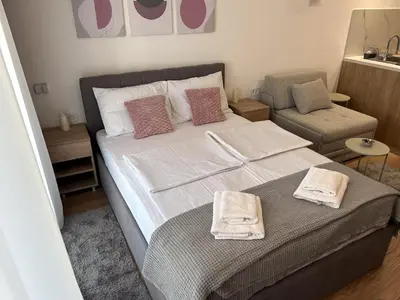 a bedroom with a large bed and a chair at V Park Lux Apartman in Belgrade