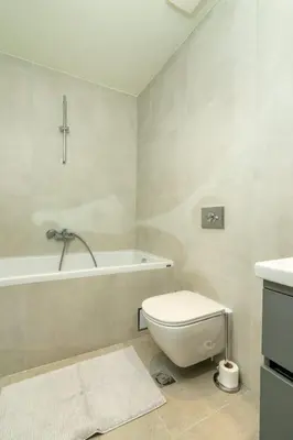a white bathroom with a toilet and a bath tub at Libera Luxe Residence in Belgrade