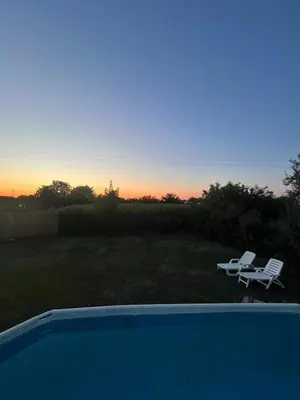 a pool with two chairs and a table and a sunset at Kuca sa bazenom Oazis in Pećinci