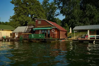 a house on a dock on a body of water at Homey house boat, great location in Ada Ciganlija