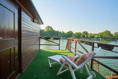 a couple of chairs sitting on a porch next to the water at Homey house boat, great location in Ada Ciganlija