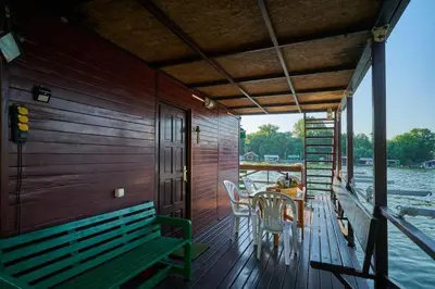 a wooden deck with a table and chairs on a boat at Homey house boat, great location in Ada Ciganlija