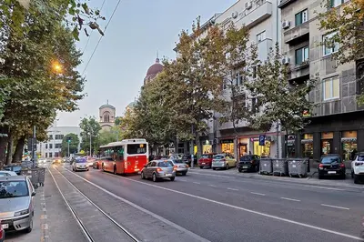 a red bus driving down a city street with cars at Skadarlija discovery Beograd centar lux in Belgrade
