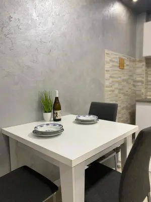 a white table with plates and a bottle of wine at Infinity Apartman Obrenovac, sa parkingom privatnim in Obrenovac