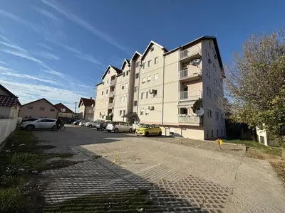 a large building with cars parked in a parking lot at Infinity Apartman Obrenovac, sa parkingom privatnim in Obrenovac