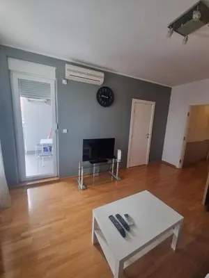 a living room with a white table and a tv at Laguna in Bežanija