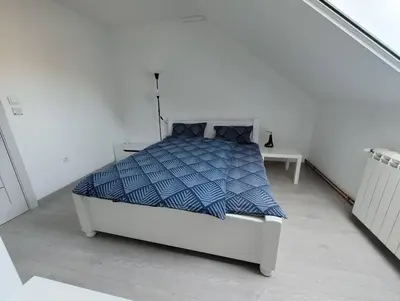 a white bedroom with a bed with a blue comforter at Miki Private Room in Belgrade