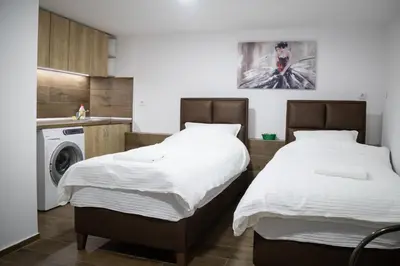 two beds in a kitchen with a washing machine at Apartman Centar 18 in Ub