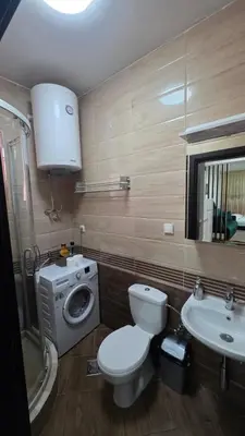 a bathroom with a toilet and a sink and a washing machine at Apartman Lela in Belgrade