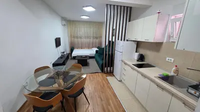a kitchen with a table and a living room at Apartman Lela in Belgrade