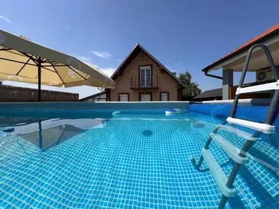 a swimming pool with two chairs in front of a house at Villa Popovic - apartments Fruska gora in Sremski Karlovci