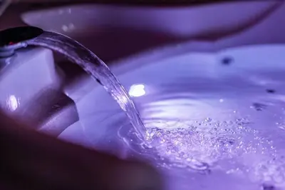 a stream of water pouring into a purple sink at Zebrano Spa in Novi Beograd