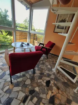 a room with chairs and a table and windows at Kućica Osmeha in Donja Ralja