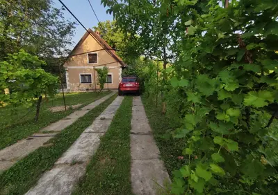 a road in front of a house with a red car at Kućica Osmeha in Donja Ralja