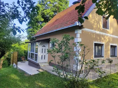 a small yellow house with a porch in a yard at Kućica Osmeha in Donja Ralja