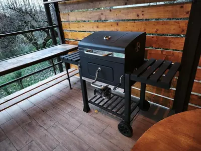 a grill sitting on a porch next to a bench at Kućica Osmeha in Donja Ralja