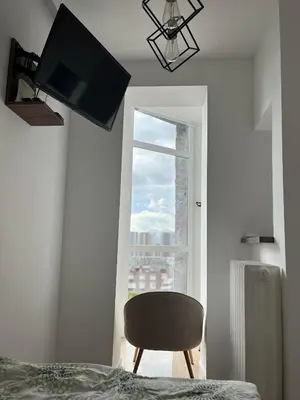 a bedroom with a chair and a window at MUNJA Apartman in Belgrade