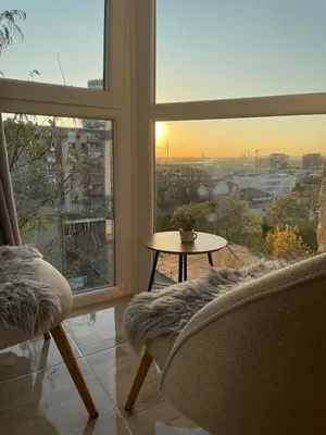 a living room with a large window and a table and chairs at MUNJA Apartman in Belgrade