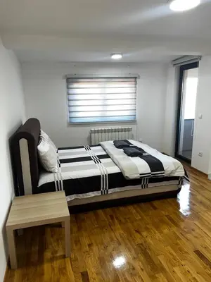 a bedroom with a large bed and a wooden floor at Apartman Dami in Belgrade
