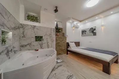a white bathroom with a tub and a bed at Lisa Zemun Spa Apartment in Zemun