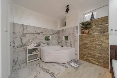 a bathroom with a white tub and marble walls at Lisa Zemun Spa Apartment in Zemun