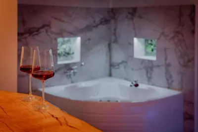 two wine glasses sitting on a table next to a bath tub at Lisa Zemun Spa Apartment in Zemun