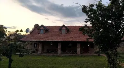 an old house with a roof on a field at Tamiški mir in Staji°evo
